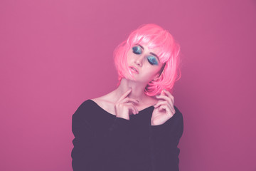 Pop style woman in a pink wig and black clothes posing on a camera isolated