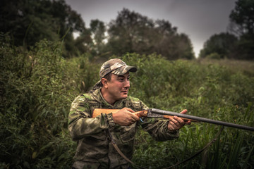 Hunting hunter shooting in reed swamp tall grass during hunting season
