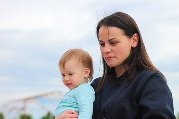 smiling mother with cute baby in her arms outdoors
