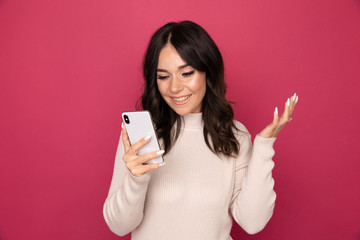 Fototapeta premium Portrait of pretty happy person using phone isolated on the pink background