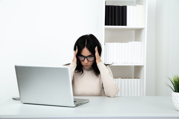 Sad and stressed woman in office sitting at the table and working till late