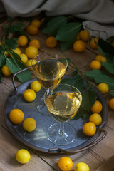 Cherry plum liqueur in small glasses and cherry plum on a wooden background. Rustic style.