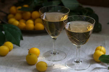 Cherry plum liqueur in small glasses and cherry plum on a wooden background. Rustic style.
