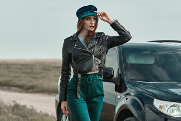 High fashion portrait of brunette woman outside in leather black jacket and trendy hat. Outdoor fashion.