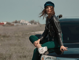 High fashion portrait of brunette woman outside in leather black jacket and trendy hat. Outdoor...