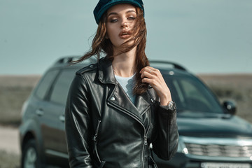 High fashion portrait of brunette woman outside in leather black jacket and trendy hat. Outdoor...