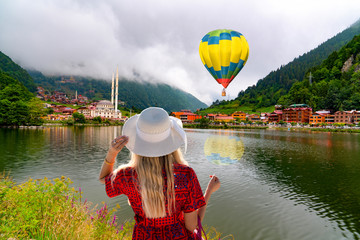 Panoramic view of Uzungol which is a tourist attraction in Trabzon, Turkey. Girl in white hat watching lake and the hot air balloon. © Bilal