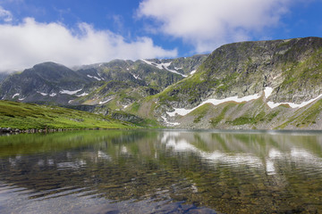 Beautiful reflection of a mountain on Rila mountain in the Kidney lake, one of seven Rila lakes, distant Lakes peak, transparent, clear water and underwater stones