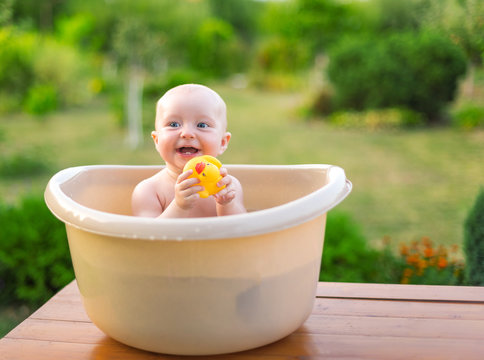 Baby bathes in a bath in the garden on a summer evening.