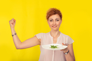 Woman holding a white plate with green salad on it