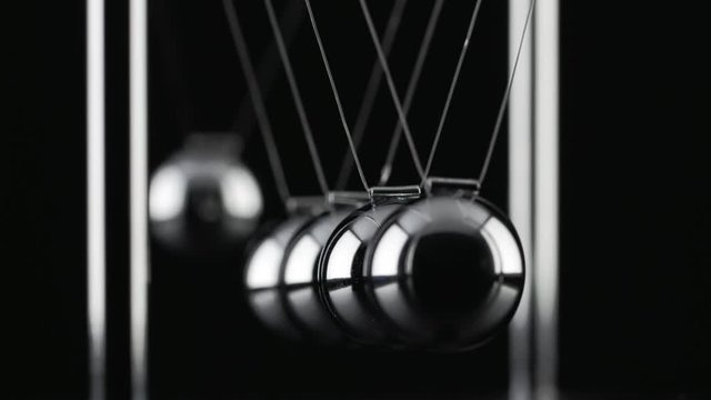 The chrome balls of a Newton&rsquo;s Cradle colliding in slow motion
