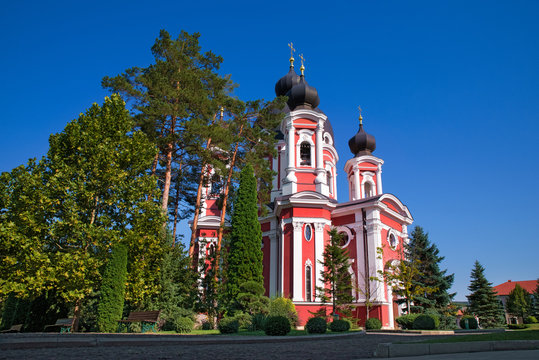 Orthodox Curchi monastery in Moldova with the sun shining at the crosses, green trees and blue sky