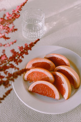 Vintage style sill life of a fruit plate with grapefruit slices, a glass of water and decorative flowers