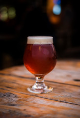 amber beer in tulip glass, craft beer on the patio, patio table with beer, patio lights,...