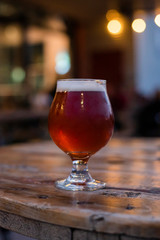 amber beer in tulip glass, craft beer on the patio, patio table with beer, patio lights, microbrewery, people in the background