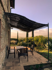 Fototapeta na wymiar Canopy with chairs and tables of a stone cottage in the Italian countryside.