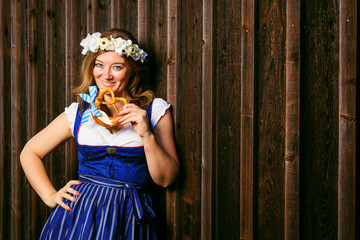 Obraz premium Young woman with pretzel on a wood background .Oktoberfest concept