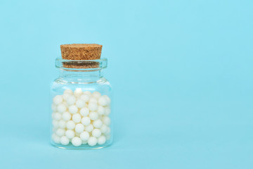 Homeopathy eco medicine concept - classical homeopathy pills in vintage glass bottles on blue...