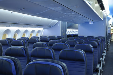 Empty commercial airplane cabin interior with blue leather seats on a widebody commercial aircraft. 