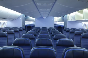 Fotobehang Lege commerciële vliegtuigcabine interieur met blauwe lederen stoelen. Twee gangpaden en open bovenbakken © Martin