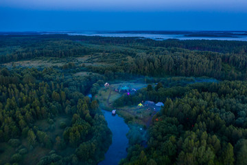 Aerial view of the forest, field and river covered with layers of thick morning fog