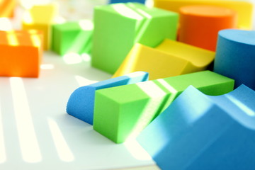 Obraz premium Puzzle games from geometric colorful shapes on a white table, selective focus.