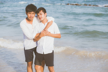 Homosexual portrait young asian couple standing hug together on beach in summer, asia gay going tourism for leisure and relax with romantic and happiness in vacation at sea, LGBT concept.