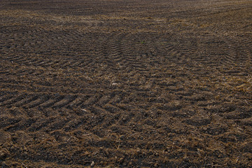 Close up top view of tire pattern from heavy tractor wheel mark trail on agricultural soil.