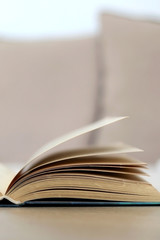 Open book on a living room table. Selective focus.