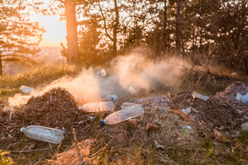 A bunch of burning leaves next to a bunch of plastic bottles in the forest.