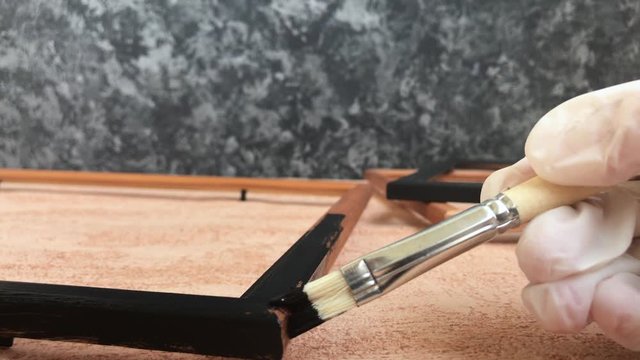 Painting a pictures frame with artistic brush. Hand made in the design studio. 
