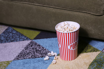 Bucket with popcorn on floor in room