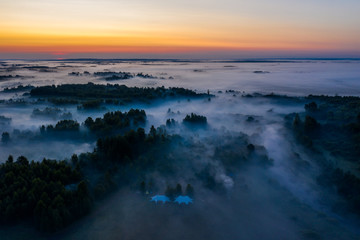 Fototapeta premium Fog floats over the forest and a field and a star-shaped tent