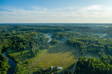 Fog floats over the forest and a field and a star-shaped tent