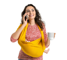 Young mother with little baby in sling talking by mobile phone on white background