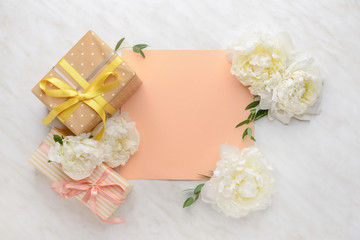 Gift boxes, blank card and beautiful flowers on light background