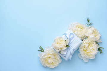 Gift box and beautiful flowers on color background