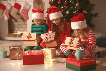 Fototapeta na wymiar Cute little children opening Christmas gifts at home