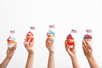 Female hands with tasty patriotic cupcakes on white background