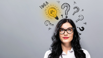 Idea light bulbs with question marks with young businesswoman in a thoughtful face