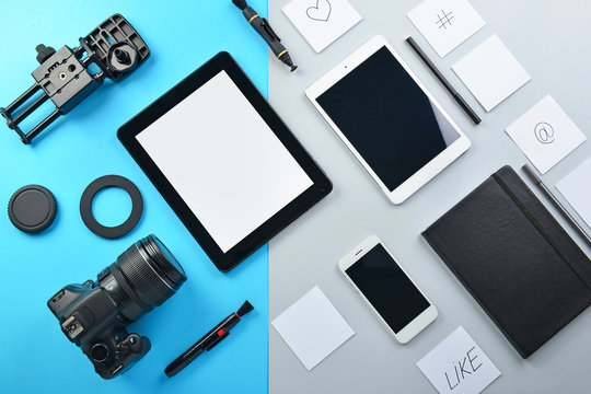 Tablet computers, mobile phone and set of photographer's equipment on color background