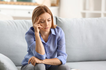 Stressed woman sitting on sofa at home