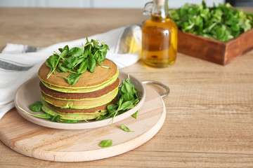 Plate with tasty green pancakes on table