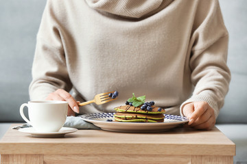 Fototapeta na wymiar Woman eating tasty green pancakes at table