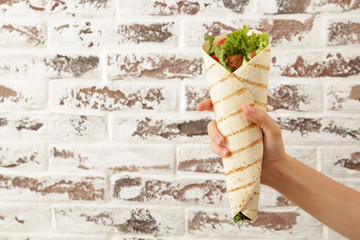 Female hand with tasty falafel pita against brick wall