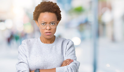 Fototapeta premium Young beautiful african american woman wearing glasses over isolated background skeptic and nervous, disapproving expression on face with crossed arms. Negative person.