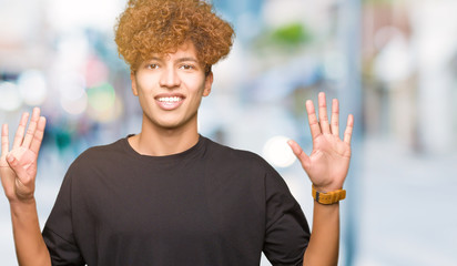 Young handsome man with afro hair wearing black t-shirt showing and pointing up with fingers number...