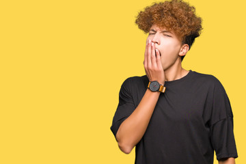 Young handsome man with afro hair wearing black t-shirt bored yawning tired covering mouth with hand. Restless and sleepiness.