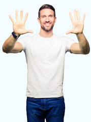 Handsome man wearing casual white t-shirt showing and pointing up with fingers number ten while smiling confident and happy.