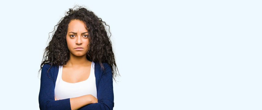Young beautiful girl with curly hair skeptic and nervous, disapproving expression on face with crossed arms. Negative person.